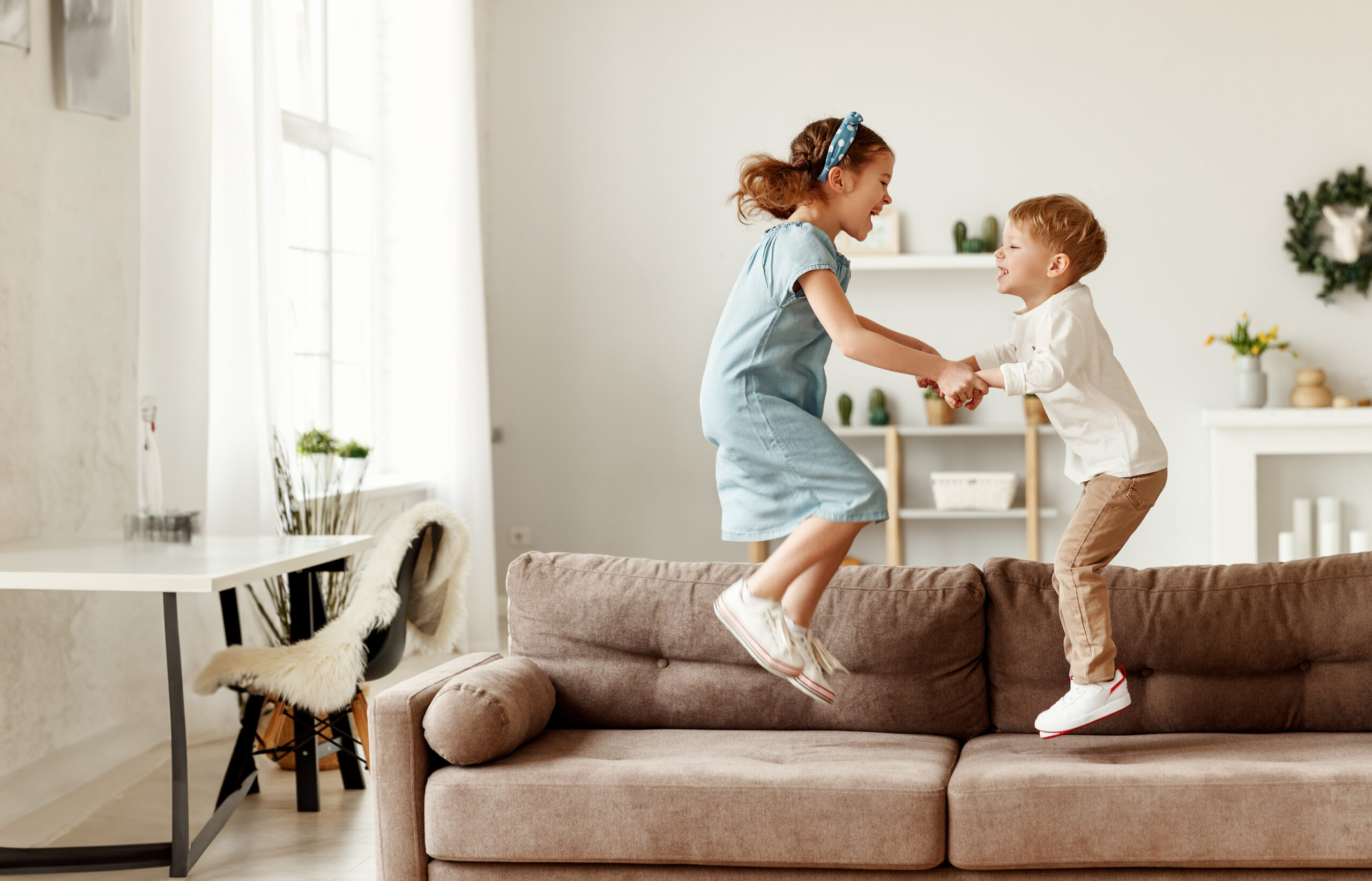 happy siblings jumping on sofa
